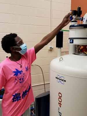 Denis Toussaint, chemistry student at Utica University in New York, loads a sample in an NMR instrument. 
