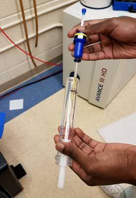 Denis Toussaint, chemistry student at Utica University in New York, holds a sample ready for NMR analysis